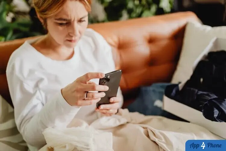 Femme inquiète utilisant un smartphone sur un canapé