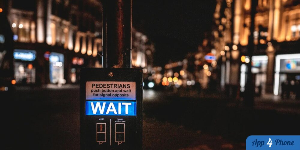Signal piétonnier affichant « WAIT » dans une rue nocturne
