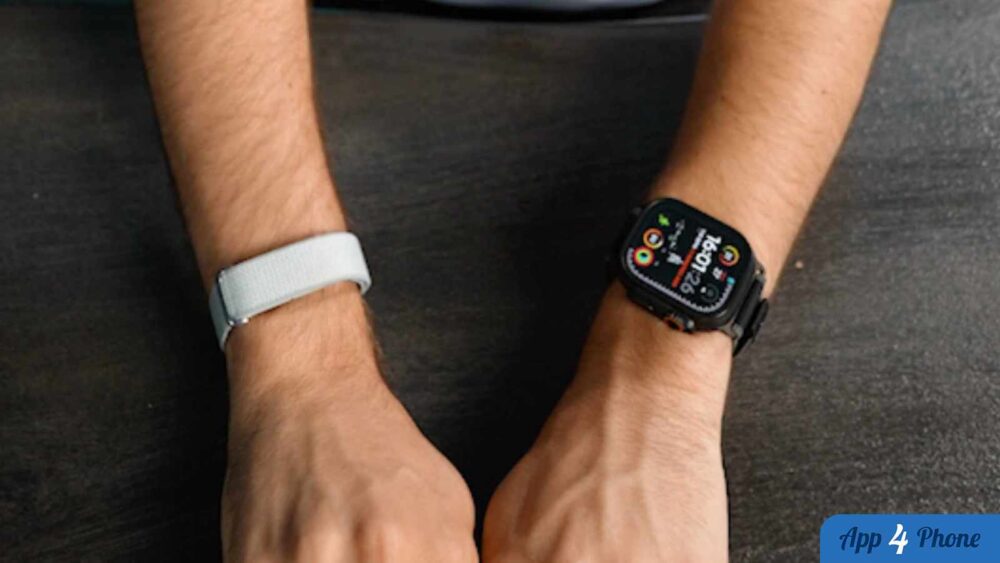 Deux bracelets connectés portés aux poignets, dont un Fitbit