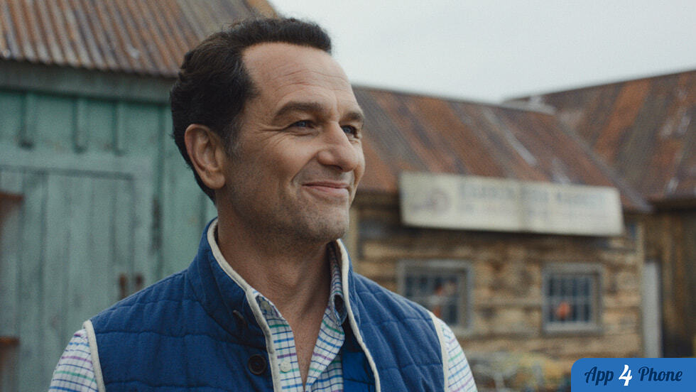 Un homme souriant devant des bâtiments anciens
