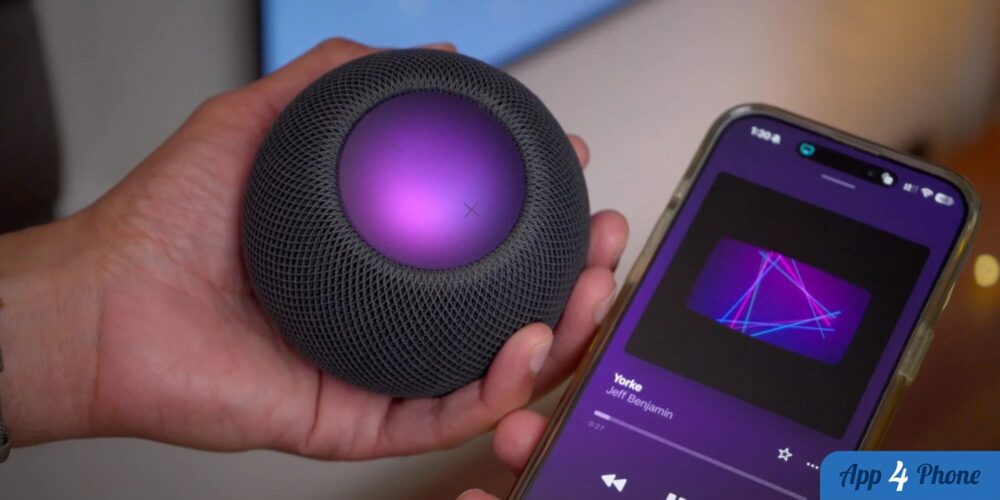HomePod noir tenu en main près d’un iPhone affichant de la musique