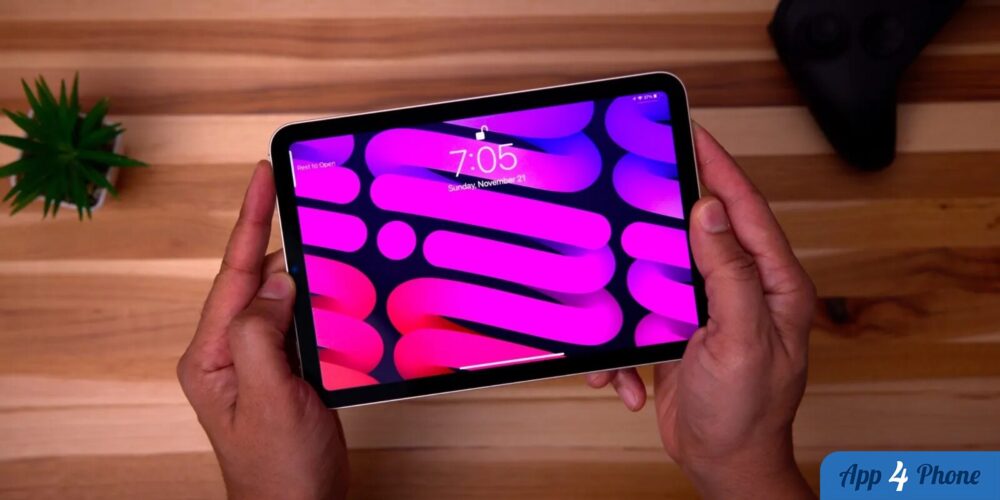 iPad mini tenu par deux mains, écran coloré affichant l’écran verrouillé