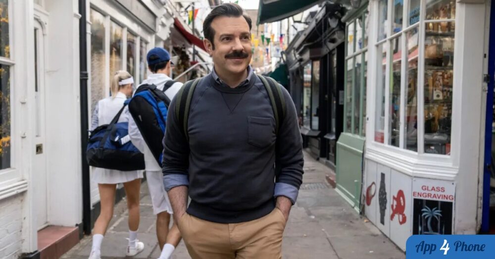 Ted Lasso marche dans une rue londonienne avec son sac à dos
